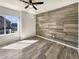A modern bedroom featuring a wood accent wall, ample sunlight, and stylish flooring at 5470 Danube St, Denver, CO 80249
