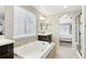 Bright bathroom featuring a soaking tub, dark vanity, and a view into the bedroom at 60 Stewart Way, Erie, CO 80516