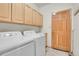 Laundry room with modern appliances, wood cabinets, and door at 31139 Tahoe Ct, Evergreen, CO 80439