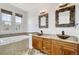 Bathroom featuring a double sink vanity, granite counters, wooden cabinets, framed mirrors and soaking tub at 12317 W Gould Ave, Littleton, CO 80127