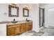 Bathroom featuring a double sink vanity, granite counters, wooden cabinets, framed mirrors and walk-in shower at 12317 W Gould Ave, Littleton, CO 80127