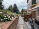 Townhome exterior with a side patio, landscaped walkway, and white flowers on a retaining wall at 12317 W Gould Ave, Littleton, CO 80127