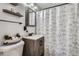 Bathroom featuring rustic vanity, decorative shower curtain, and modern fixtures, offering a blend of style and function at 6761 Harlan St, Arvada, CO 80003