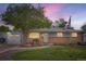 Charming brick home with well-maintained lawn, mature tree, and walkway, accented with a Colorado State flag at 6761 Harlan St, Arvada, CO 80003