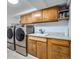 Functional laundry room with modern washer and dryer set, sink, and ample cabinet storage at 6761 Harlan St, Arvada, CO 80003