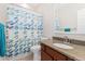 Bright bathroom featuring a granite-topped vanity and tub with a colorful, patterned shower curtain at 8851 E 33Rd Ave, Denver, CO 80238