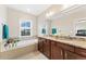 Modern bathroom features double sinks, granite countertops, and a luxurious soaking tub beneath a window at 8851 E 33Rd Ave, Denver, CO 80238