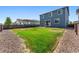 Backyard features a large grassy area, gravel borders, and a blue two-story home in the background at 26857 E Maple Ave, Aurora, CO 80018