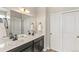 Bright bathroom featuring double sinks, dark cabinets, white countertops, and a large mirror at 26857 E Maple Ave, Aurora, CO 80018