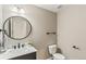 Stylish powder room with a round mirror, modern fixtures, and a sleek vanity with marble countertop at 26857 E Maple Ave, Aurora, CO 80018