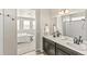 Bright bathroom featuring double sinks, dark cabinets, and a shower with white tiled walls at 26857 E Maple Ave, Aurora, CO 80018