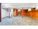 Unfinished basement featuring exposed pillars, patterned carpeting, and wood paneled walls at 500 S Decatur St, Denver, CO 80219