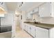Functional galley kitchen with white cabinets and essential appliances with a view through to the living area at 8100 W Quincy Ave # A8, Littleton, CO 80123