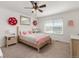 Charming bedroom featuring a cozy bed with pink accents, a bright window, and decorative wall flowers at 15446 Coopers Hawk Way, Parker, CO 80134