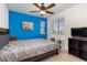 Bright bedroom featuring a blue accent wall, plush gray bedding, and a window with neighborhood views at 15446 Coopers Hawk Way, Parker, CO 80134