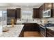 Modern kitchen featuring granite countertops, stainless steel appliances, and dark wood cabinets at 15446 Coopers Hawk Way, Parker, CO 80134
