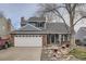 Charming home featuring a brick-accented facade, two-car garage and a well-maintained lawn and rock garden at 8985 W Quarto Pl, Littleton, CO 80128