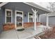 Inviting covered front porch with brick base, decorative columns, and a glass front door at 8985 W Quarto Pl, Littleton, CO 80128