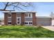 Two-story home features a brick and gray wood facade, lush front yard, and attached two-car garage at 12235 Garfield Pl, Thornton, CO 80241
