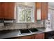 Close up of the sink with wood cabinets and a gray tile backsplash at 12235 Garfield Pl, Thornton, CO 80241