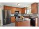 Modern kitchen featuring wood cabinets, stainless steel appliances, gray backsplash, and a center island at 12235 Garfield Pl, Thornton, CO 80241