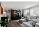 Bright living room with gray walls, hardwood floors, a large window with sheer curtains, and comfortable gray furniture at 12235 Garfield Pl, Thornton, CO 80241