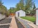 Well-maintained backyard with a wooden pathway, decorative rock borders, lush turf, and a charming shed at 4747 S Elati St, Englewood, CO 80110