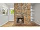 Close-up of a stone fireplace with a cozy fire, built-in shelves, and natural light from the window at 2678 S Xanadu Way # C, Aurora, CO 80014