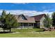 Spacious backyard with lush green grass, mature trees, and a covered patio at 690 Antelope Dr, Bennett, CO 80102