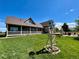 Expansive backyard with lush lawn, a windmill accent, and covered patio at 690 Antelope Dr, Bennett, CO 80102