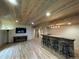 Finished basement featuring a stone bar, wood ceiling, wood-look flooring, and entertainment center at 690 Antelope Dr, Bennett, CO 80102