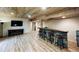 Finished basement featuring a stone bar, wood ceiling, wood-look flooring, and entertainment center at 690 Antelope Dr, Bennett, CO 80102