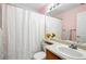 Cozy bathroom with pink walls, white shower curtain, and vanity with a sink at 13931 E 104Th Dr, Commerce City, CO 80022