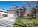 Charming two-story home featuring a well-maintained front yard, brick accents, and a two-car garage on a sunny day at 13931 E 104Th Dr, Commerce City, CO 80022