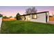 View of backyard with grass lawn, white house with black trim, and evening sky at 6369 W 69Th Ave, Arvada, CO 80003