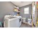 Functional laundry room with side-by-side washer and dryer and overhead storage shelves at 18096 E 104Th Way, Commerce City, CO 80022