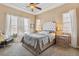 This bedroom features a tray ceiling, carpet flooring, and large windows dressed with white curtains at 7743 S Quantock Way, Aurora, CO 80016