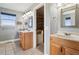 Bright bathroom featuring double vanities, stylish mirrors, and an adjacent walk-in closet at 1212 N County Road 125, Bennett, CO 80102