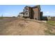 View of the side and rear of this house with a dirt driveway and partial lawn at 1212 N County Road 125, Bennett, CO 80102