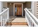 Elegant wooden front door framed by white railings and a sunny porch at 1212 N County Road 125, Bennett, CO 80102