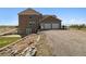 View of house showing garage, lawn, rock wall, and gravel driveway at 1212 N County Road 125, Bennett, CO 80102