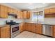 Well-equipped kitchen featuring wooden cabinets, stainless steel appliances, and a bright window at 1212 N County Road 125, Bennett, CO 80102