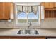 Kitchen sink area with wooden cabinets, stainless steel appliances, and a faucet with backyard views at 1212 N County Road 125, Bennett, CO 80102