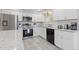 Bright kitchen showcasing stainless steel appliances, white cabinets, granite counters, and tile flooring at 8506 Eaton St, Arvada, CO 80003