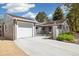 Charming home with gray brick, well-manicured landscaping, and a driveway leading to an attached garage at 4500 Zephyr St, Wheat Ridge, CO 80033
