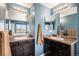 This bathroom features dual sinks, dark cabinets, bright lighting, and mirrors above each sink at 2516 Mountain Sky Dr, Castle Rock, CO 80104