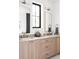 Double vanity bathroom featuring light wood cabinets, dual mirrors, and a black frame window at 1680 S Humboldt St, Denver, CO 80210