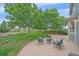 Relaxing backyard featuring mature trees, a patio set, and lush green grass at 9869 Burberry Way, Highlands Ranch, CO 80129