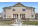 Tan two-story townhome with green accents, stone walkway, and landscaping at 15800 E 121St Ave # 3J, Brighton, CO 80603