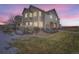 Two-story townhome with lighted windows and a landscaped yard at dusk at 15800 E 121St Ave # 3J, Brighton, CO 80603
